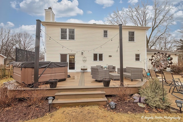 rear view of house with a deck, fence, an outdoor living space, a chimney, and a hot tub