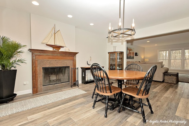 dining room featuring a fireplace, recessed lighting, an inviting chandelier, light wood-type flooring, and baseboards