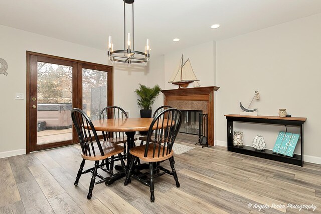 dining space with light wood finished floors, baseboards, an inviting chandelier, a fireplace, and recessed lighting