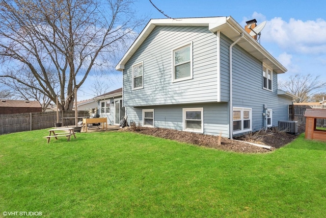 rear view of property featuring a chimney, a lawn, cooling unit, and fence private yard