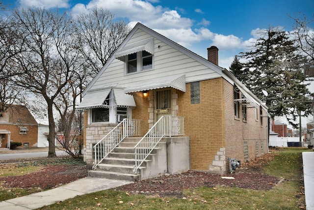 bungalow featuring brick siding and a chimney