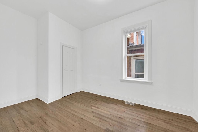 unfurnished room featuring visible vents, baseboards, and wood finished floors