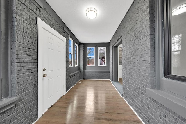 interior space with brick wall and wood finished floors