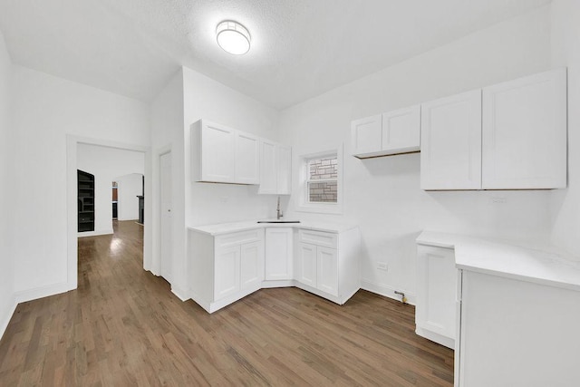 kitchen with arched walkways, light countertops, wood finished floors, and white cabinets