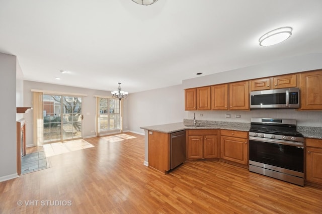 kitchen featuring appliances with stainless steel finishes, brown cabinetry, and light wood finished floors