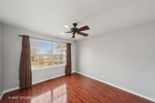 spare room featuring ceiling fan, visible vents, baseboards, and wood finished floors