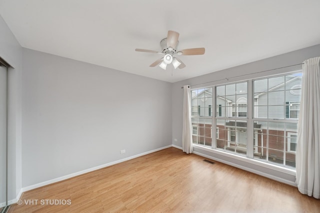 empty room with visible vents, baseboards, light wood-style floors, and ceiling fan