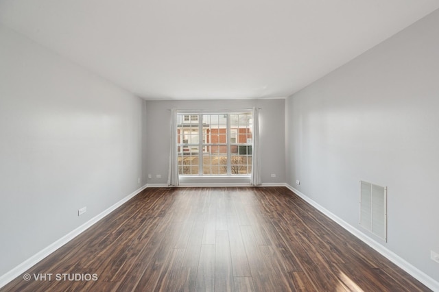 empty room featuring visible vents, baseboards, and dark wood-style flooring