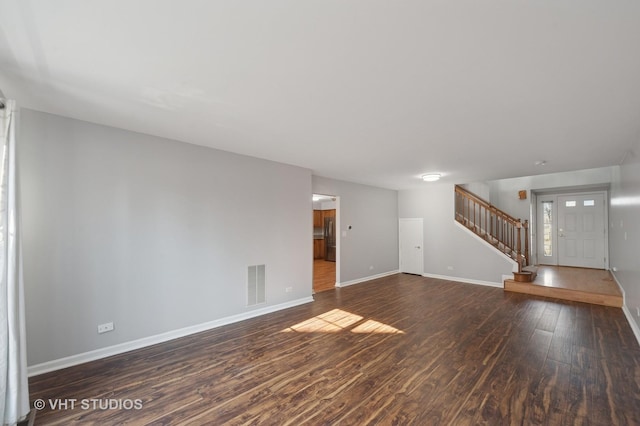 unfurnished living room with stairway, wood finished floors, visible vents, and baseboards