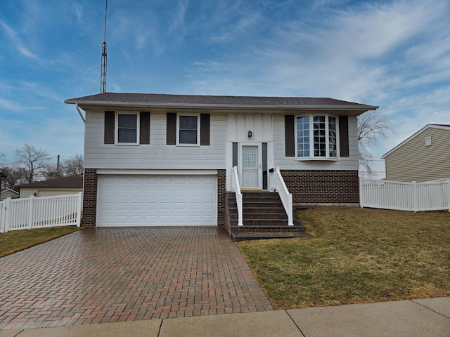 raised ranch featuring decorative driveway, brick siding, an attached garage, a front yard, and fence