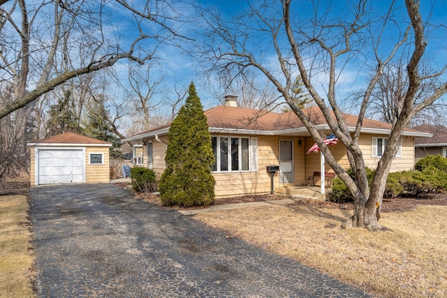 single story home with an outbuilding, aphalt driveway, a chimney, and a garage