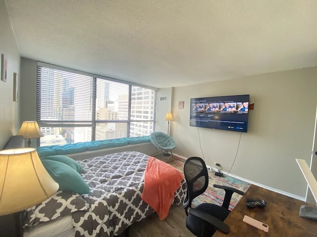 bedroom with visible vents, a textured ceiling, baseboards, and wood finished floors