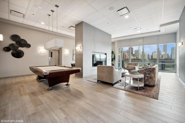 playroom featuring a high ceiling, a paneled ceiling, wood finished floors, and visible vents