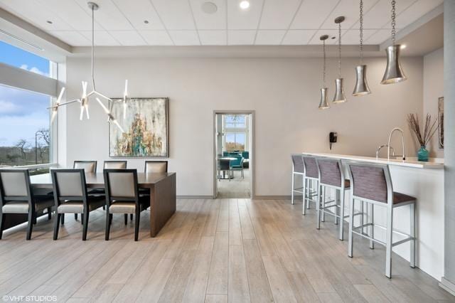 dining area with plenty of natural light, wood finished floors, a towering ceiling, and baseboards