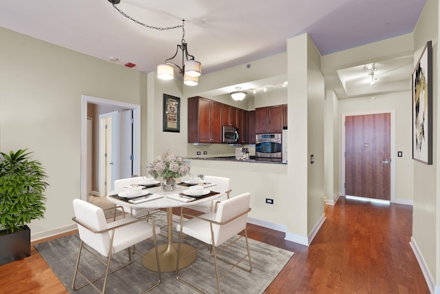 dining space featuring a notable chandelier, baseboards, and dark wood-style flooring