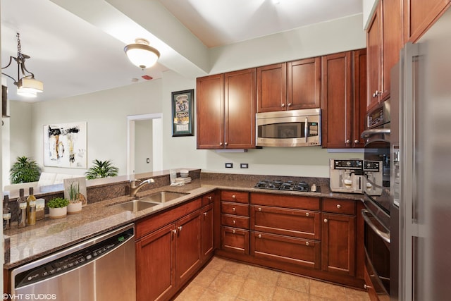 kitchen with stainless steel appliances, a peninsula, a sink, dark stone counters, and decorative light fixtures