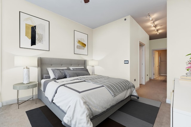 carpeted bedroom featuring rail lighting and baseboards