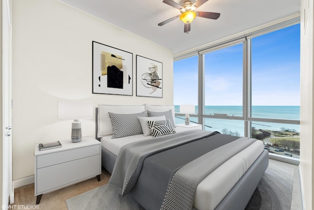 bedroom with floor to ceiling windows, a water view, light carpet, and ceiling fan