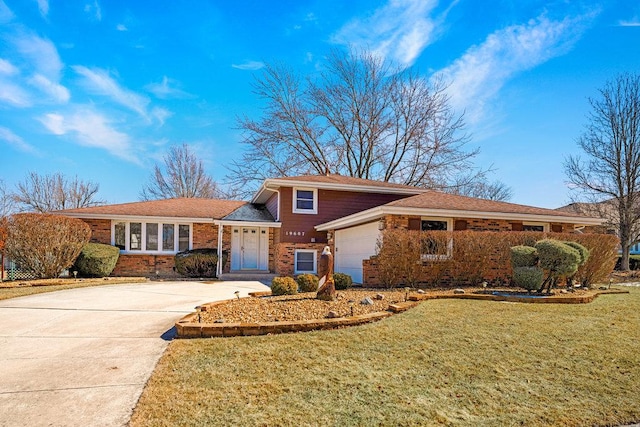 tri-level home featuring a garage, brick siding, driveway, and a front lawn