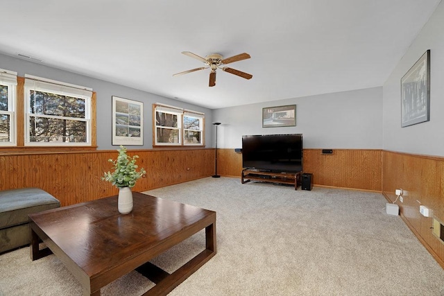 living area with carpet, a wainscoted wall, wood walls, and visible vents