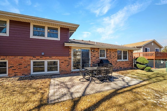 back of house featuring a patio area, brick siding, fence, and a lawn