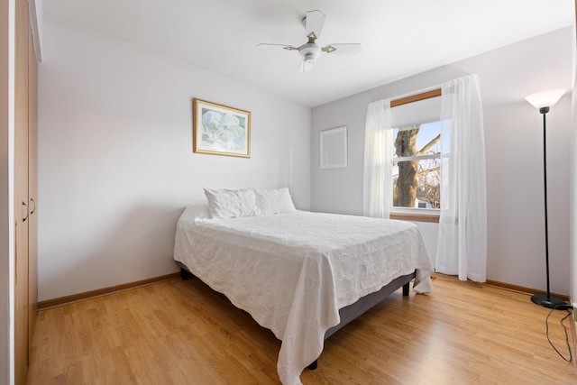 bedroom featuring a ceiling fan, light wood-style flooring, and baseboards