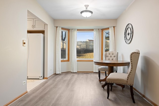 dining space with light wood finished floors and baseboards