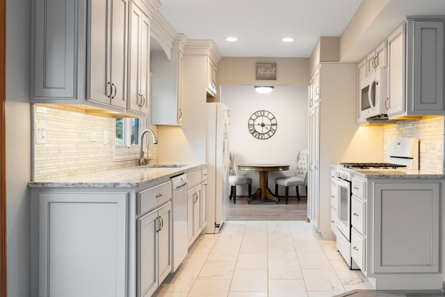 kitchen with white appliances, light stone countertops, marble finish floor, gray cabinets, and a sink