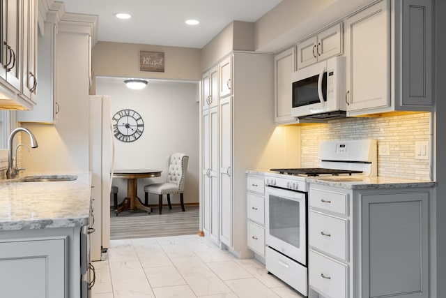 kitchen featuring marble finish floor, white appliances, a sink, and gray cabinetry