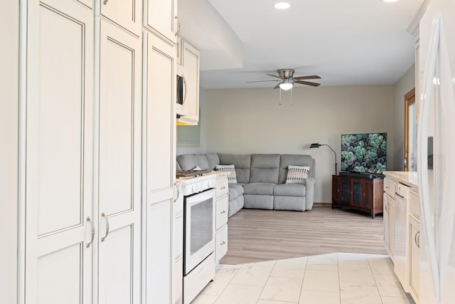 kitchen with white appliances, ceiling fan, open floor plan, light countertops, and white cabinetry