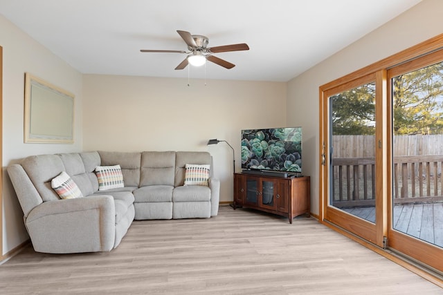 living area with a ceiling fan, light wood-style flooring, and baseboards