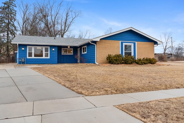 ranch-style house featuring brick siding and a front yard