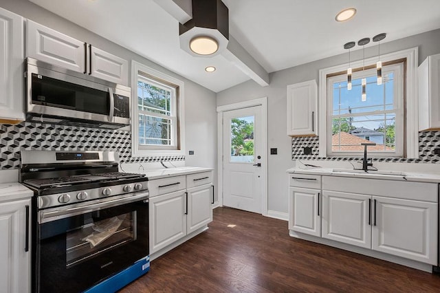 kitchen with tasteful backsplash, dark wood finished floors, appliances with stainless steel finishes, vaulted ceiling with beams, and white cabinetry