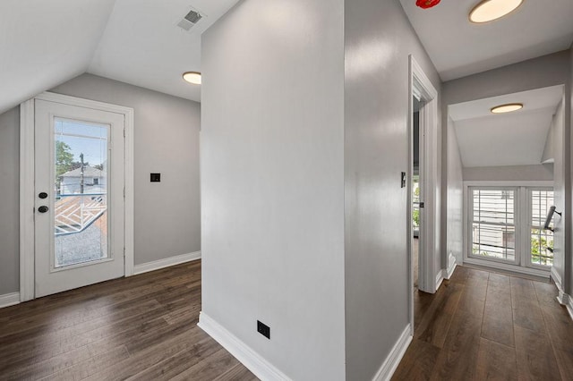 corridor featuring dark wood-style flooring, visible vents, vaulted ceiling, and baseboards