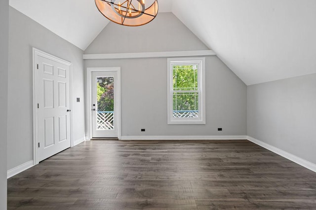 bonus room featuring a wealth of natural light, dark wood finished floors, and an inviting chandelier