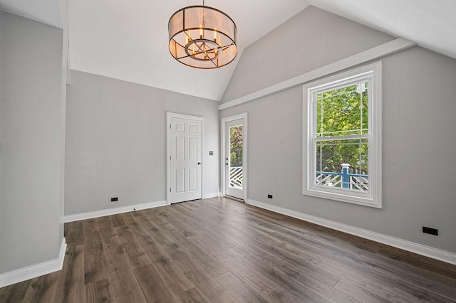 spare room featuring dark wood-type flooring, vaulted ceiling, baseboards, and an inviting chandelier