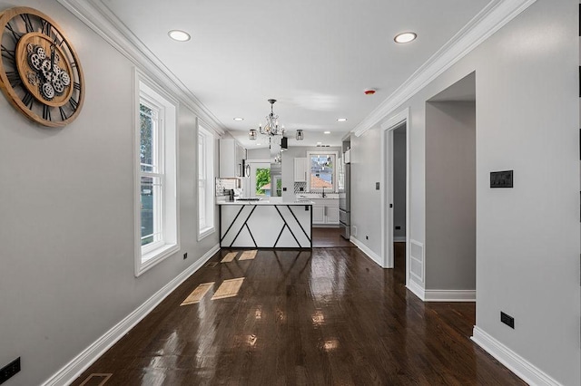 interior space with a notable chandelier, ornamental molding, dark wood-type flooring, and baseboards