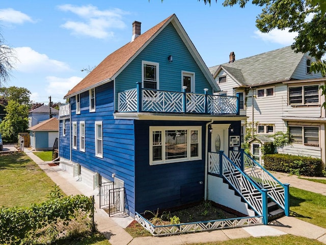 view of front of home with a balcony and a front yard