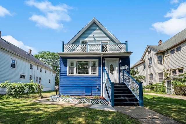 shotgun-style home featuring a balcony and a front yard