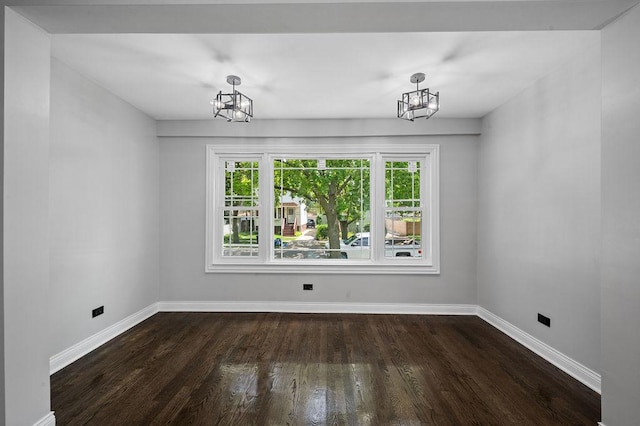 unfurnished dining area with baseboards, dark wood-type flooring, and a notable chandelier