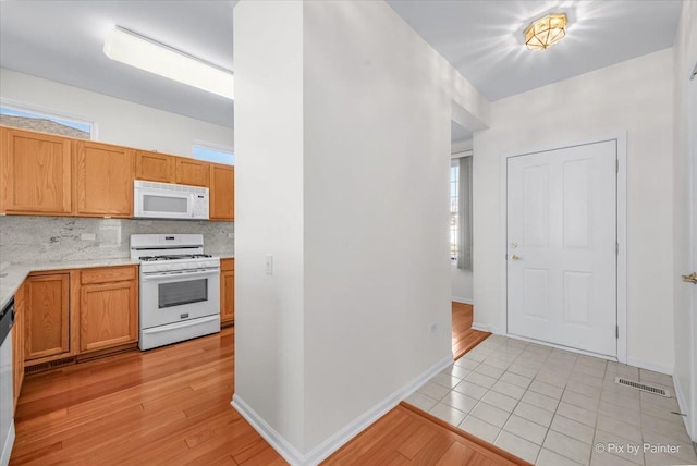 kitchen with light countertops, visible vents, decorative backsplash, light wood-type flooring, and white appliances