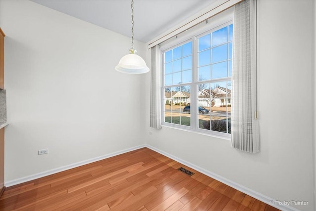 unfurnished dining area with light wood-style flooring, visible vents, and baseboards