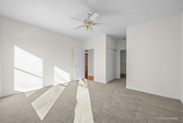 carpeted spare room featuring ceiling fan and baseboards