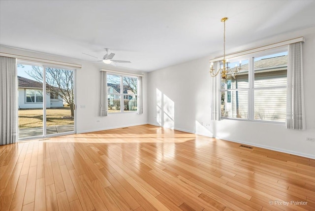 unfurnished living room featuring ceiling fan with notable chandelier, light wood finished floors, visible vents, and baseboards