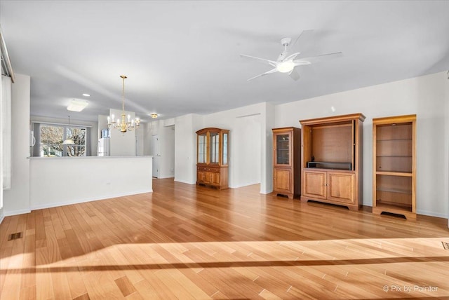 unfurnished living room with ceiling fan with notable chandelier, light wood-type flooring, visible vents, and baseboards