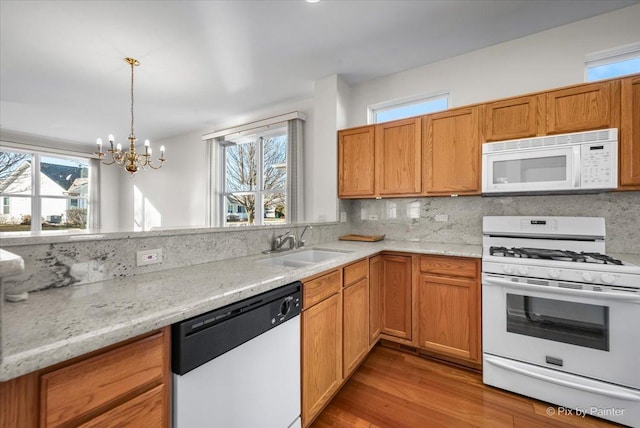 kitchen with a healthy amount of sunlight, white appliances, decorative backsplash, and a sink