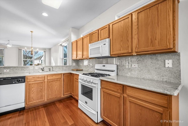 kitchen with white appliances, backsplash, a sink, and dark wood finished floors