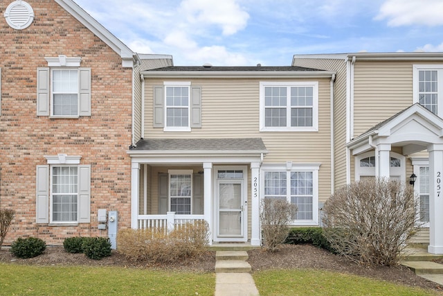 multi unit property featuring brick siding, roof with shingles, and a porch