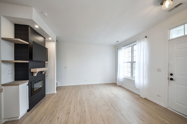 unfurnished living room with a large fireplace, baseboards, visible vents, light wood-style floors, and recessed lighting