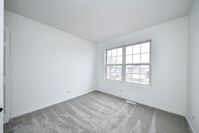 unfurnished room with carpet flooring, visible vents, and baseboards